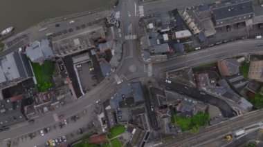 Kuşbakışı manzara, Belçika 'nın Dinant kentinin merkezini gösteriyor. Arabalar Meuse nehrinden geçen bir köprüden geçiyor, canlı bir ortamda kentsel yaşam ve manzaraları vurguluyor..