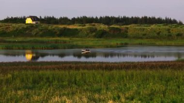 Balıkçı teknesini Danimarka 'daki bir nehrin sakin sularına götürür. Güneş batar ve yeryüzüne sıcak bir ışıltı saçar..