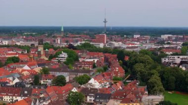 Munster şehrinin havadan görünüşü, Almanya. Kırmızı çatılar ve yeşil ağaçlar mavi bir gökyüzünün altında uzanıyor. Fernsehturm televizyon kulesi uzaktan görülebiliyor..