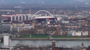 Cologne Lanxess Arena 'nın havadan görünüşü, spor ve konser yeri ve Rhine Nehri kentsel mimariyle çevrili..