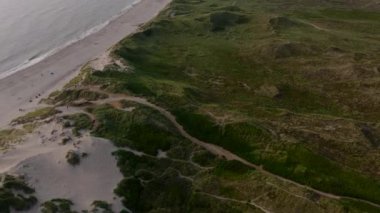 Danimarka 'daki Ringkobing Fjord kıyı şeridinin hava perspektifi, kum tepeleri ve yeşil bitki örtüsüyle kara ve denizin buluşma noktasını gözler önüne seriyor..