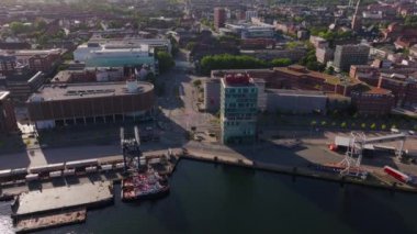 Kargo gemilerini yükleyen vinçlerle Kiel limanının havadan görüntüsü ve çevre şehir manzarası. Kamera şehir manzarasını yakalar.