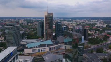 Hava görüntülerinde Vilnius modern iş merkezi, etkileyici gökdelenler ve canlı alışveriş merkezleri yer alıyor, kentsel manzara ve mimari güzellikler vurgulanıyor.