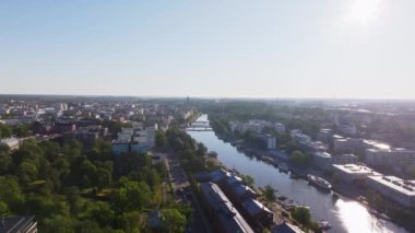 Aura Nehri, Finlandiya 'daki Turku şehir merkezinde akan güneş ışığını yansıtır. Nehrin etrafını saran binalar ve bitkiler.