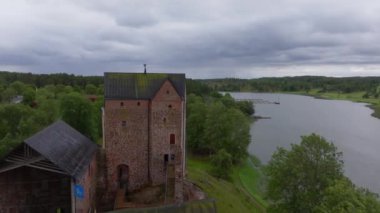 Kastelholm Şatosu, bulutlu bir yaz gününde fiyortların suyunu görmezden gelir. Ortaçağ mimarisini ve zengin tarihini yemyeşil bir manzarayla gözler önüne serer..