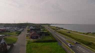 Danimarka 'daki Ringkobing Fjord' u çevreleyen kıyı yolunun havadan görünüşü. Arabalar yol boyunca gidiyor ve bir bisikletçi su boyunca sürüyor..