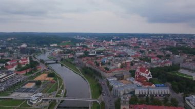 Bulutlu bir günde Vilnius 'tan akan Neris Nehri şehirlerin kırmızı çatılarını ve kiliselerini vurgular ve kentsel bir ortamda tarihi ve kültürün büyüleyici bir karışımını yaratır..