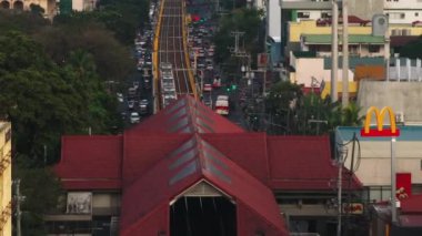 Manila 'da işlek bir caddenin üstündeki yüksek tren hattı. Filipinler 'deki hareketli şehir sahnesinde araçlar ve yayalar hareket ediyor.