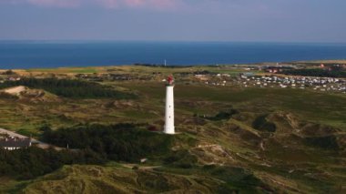 Lyngbjerg Fyr deniz feneri güneşli bir günde dimdik ayakta duruyor. Resimli Ringkobing Fjord 'a bakıyor. Kuzey Denizi açık mavi gökyüzüne karşı çarpıcı bir zemin oluşturur..