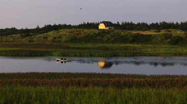 Danimarka 'da bir nehirde yelken açan balıkçılar, güneş batarken sakin sularda hafif bir uyanış yaratırlar, sıcacık, altın bir ışıkta yüzerler..