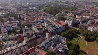 Berlin 'deki binaların üzerinde çalışan bir vinç görülüyor. Arabalar kırmızı kökler altında cadde boyunca sürüyorlar..