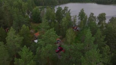 Havadan bakıldığında canlı ormanlarla çevrili büyüleyici kırmızı ahşap evler ve İsveç 'te sakin bir göl görülüyor. Yazın İskandinav kırsalının özünü yansıtıyor..