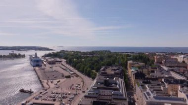 Hava görüntüleri, güneşli bir yaz gününde Helsinki 'nin canlı şehir merkezini yakalıyor. Limana yaklaşan bir feribot Baltık Denizi kıyısındaki kentsel yaşamı gözler önüne sererken arabalar sokaklarda akıyor..