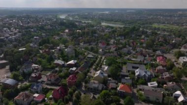 Sakin nehir, Litvanya 'nın Kaunas kentindeki bir yerleşim bölgesinden akar. Yeşiller yemyeşil ağaçlar evlerin etrafını kırmızı çatılarla çevreler..