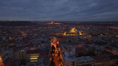 Prag şehir merkezinin hava manzarası mavi saatte aydınlanıyor. Caddelerde trafik ve arka planda Kale var..