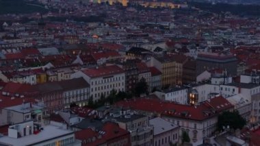 Prag çatıları mavi saat boyunca ışıldıyor, zarif mimari ve canlı şehir ışıklarını vurguluyor, muhteşem Prag Kalesi arka planda belirgin bir şekilde yükseliyor..