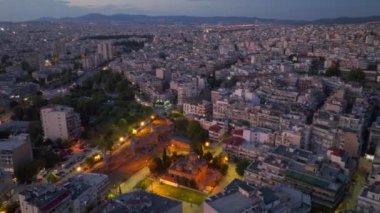 Selanik 'te alacakaranlıkta, şehir ışıkları ve konut binaları ile canlı bir şehir manzarası arasında aydınlatılmış bir rotunda sergileniyor..