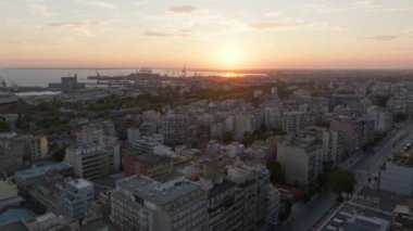 Hava görüntüleri Selanik 'i gün batımında yakalıyor, güneş termaik körfezin üzerinde batıyor ve şehrin her tarafına sıcak bir parıltı saçıyor, canlı ufuk çizgisini ve mimarisini vurguluyor..