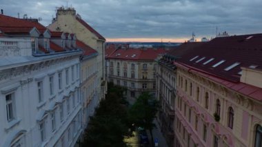Prag 'daki şehir merkezinin hava manzarası. Kamera, güneş batarken kırmızı çatıları olan tipik Çek apartmanlarından geçiyor..