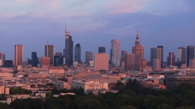 Gün batımında Varşova ufuk çizgisinin hava görüntüsü değişiyor. Kültür ve Bilim Sarayı ve modern gökdelenler renkli gökyüzüne karşıdır..