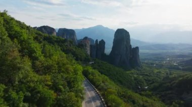 Sarmal orman yolu, Yunanistan 'daki sarp bir uçurumun tepesinde dramatik bir şekilde tünemiş bir manastırı gösteren nefes kesici Meteora kaya oluşumlarını gözler önüne seriyor..