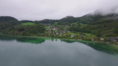 Fuschlsee 'yi Avusturya' da göl yüzeyinde yansıyan bulutlarla hava görüntüsü yakalıyor. Arka planda yükselen görkemli Alpler, Fuschl am 'da sakin ve çarpıcı bir manzara oluşturuyor..