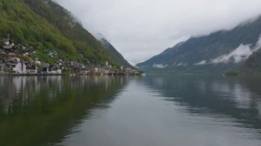 Bulutlar Avusturya 'daki Hallstatt Gölü' nün durgun yüzeyine yansıyor. Hallstatt 'ın küçük Alp kasabası kıyıya kurulmuş ve arka planda dağlar yükseliyor..