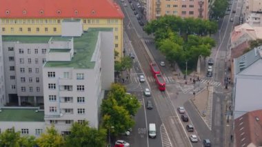 Çek Cumhuriyeti, Brno 'da bir kavşaktan geçen kırmızı bir tramvayın hava görüntüsü. Şehir manzarasında arabalar ve yayalar geziniyor..