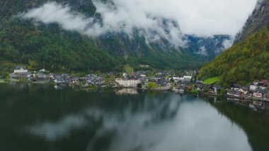 Alçak bulutlar Avusturya 'nın Hallstatt bölgesinden geçiyor ve göle yansıyor. Köy kıyıya kurulmuş, dağlarla çevrili..