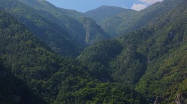 Olimpos Dağı 'nın yemyeşil yamaçları üzerindeki hava manzarası canlı bitki örtüsü ve doğal ihtişam ile dolu, sakin bir yaz manzarasını vurguluyor..