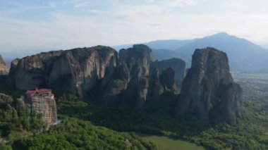 Meteora 'nın büyüleyici kaya oluşumları görkemli bir şekilde yükselir, nefes kesen doğal güzellikleri ve derin kültürel önemi yansıtan bir manastırı çerçeveler..
