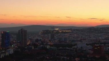 Gün batımında Bratislavas gökdelenleri ve ön plandaki renkli ve modern gökdelenlere karşı Bratislava ikonik kalesini sergiliyor..