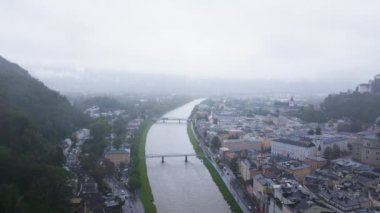 Avusturya, Salzburg 'un hava manzarası Salzach Nehri, Hohensalzburg Kalesi ve bulutlu bir gökyüzü altında büyüleyici bir mimari ile şehir manzarasını gözler önüne seriyor..