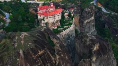 Yunanistan 'ın Meteora kentinin büyüleyici manzarası, sarp bir kaya oluşumunun tepesine tünemiş çarpıcı bir manastır sergiliyor, eşsiz manzaraları ve zengin kültürel mirası vurguluyor..