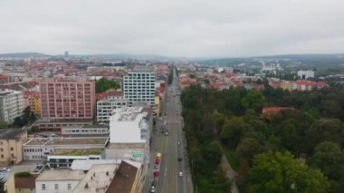 Çek Cumhuriyeti 'nin Brno kentindeki ağaçlar ve binalarla çevrili geniş bir yolda ilerleyen arabaları gösteren hava görüntüleri, canlı bir kentsel çevre ve aktif trafiği gösteriyor..
