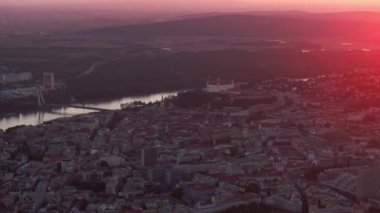 Bratislava, Slovakya başkenti, gün batımının altın renkleri altında ışıldar, canlı şehir manzarası, olağanüstü mimarisi ve akan Tuna Nehri 'nin havadan bir perspektifini gözler önüne serer..