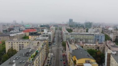 Arabalar Brno 'da çağdaş binalarla dolu geniş bir caddede yol alıyorlar. Şehir manzarası hareketli şehir dinamiklerini yakalıyor, trafik bulutlu bir gökyüzünün altında durmadan hareket ediyor..