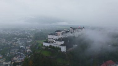 Hava görüntüleri Salzburg 'u kaplayan sisi, şehri ve Hohensalzburg Kalesi' ni kaplayan sisi gösteriyor. Sahne mistik bir ortam yaratıyor, tarihi mimari ve nefes kesici manzaralar sergiliyor..
