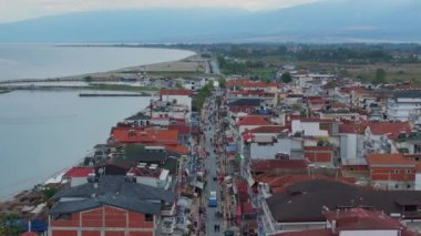 Yunanistan 'ın Paralia Katerinis kentinde kalabalık bir caddede yürüyen turistler ve yerliler. Dükkanlar ve restoranlar, Ege Denizi 'ne paralel giden cadde boyunca uzanır..