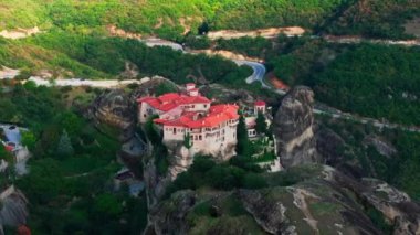 Hava görüntülerine göre, kayalık bir çıkıntının üzerinde dinlenen bir manastır var. Güneş ışığı etrafındaki manzaranın huzur dolu güzelliğini vurgulayan dinamik gölgeler oluşturuyor..