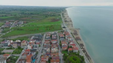 Havadan bakıldığında, yakınındaki binalar, dolambaçlı bir yol, ışıl ışıl yeşil bir alan ve çarpıcı sahil ve şehir manzarasını aydınlatan boş bir sahil görülüyor..