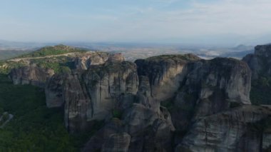 Yunanistan 'ın Meteora kentinin çarpıcı kaya oluşumlarını incelemek, arka planda doğal güzellikleri gözler önüne seren vadi ve görkemli dağlarla nefes kesici bir manzarayı gözler önüne seriyor..