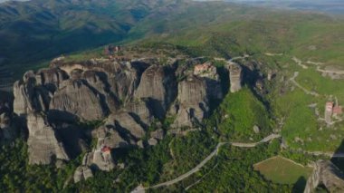 Meteora, Yunanistan 'ın havadan görünüşü. Kamera manzarayı tarıyor ve tepeye inşa edilmiş çarpıcı kaya oluşumlarını ve manastırları gösteriyor..