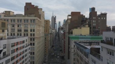 Gökyüzü görüntüsü, arka planda ikonik Empire State Binası kuleleri dururken, sarı taksilerle dolu canlı bir New York caddesini vurguluyor..