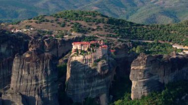 Yunanistan 'ın Meteora kentindeki bir kaya oluşumunda bulunan bir manastırın havadan görünüşü. Kamera çevredeki manzarayı gösteriyor..