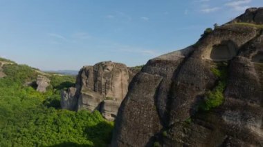 Gökyüzü manzaraları, yemyeşil vadiler ve açık mavi gökyüzünün ortasında yükselen uçurumlar ve antik manastırların yer aldığı Yunanistan 'daki nefes kesen Meteora kaya oluşumlarını vurguluyor.