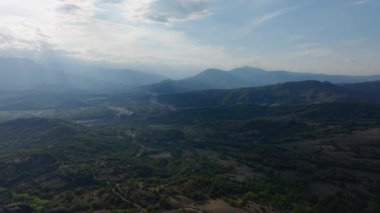 Parlak yeşil vadiyi aydınlatan güneş ışığı Yunanistan 'daki görkemli Meteora kaya oluşumlarını vurguluyor ve tarihe ve ruhaniliğe bulanmış nefes kesici bir manzarayı gözler önüne seriyor..