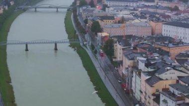 Salzburg Nehri bulutlu bir gökyüzünün altında zarif bir şekilde akan Salzburg tarihi merkezini gözler önüne seren hava manzaraları, şehirlerin çarpıcı mimarisini ve kentsel manzarayı gözler önüne seriyor..