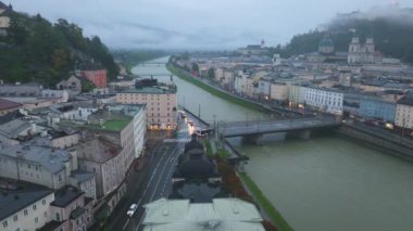 Tripod, Salzburg şehrini yüksek bir açıyla tasvir ediyor. Salzach Nehri 'nin şehir merkezinden geçtiği arka planda Hohensalzburg Kalesi yer alıyor..