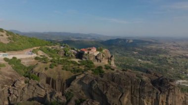 Hava perspektifi, Yunanistan 'ın Meteora kentinde dik bir kaya oluşumunda yer alan Varlaam Manastırı' nı çarpıcı bir şekilde gözler önüne seriyor. Turist arabaları aşağıdaki dolambaçlı yolda ilerliyor..